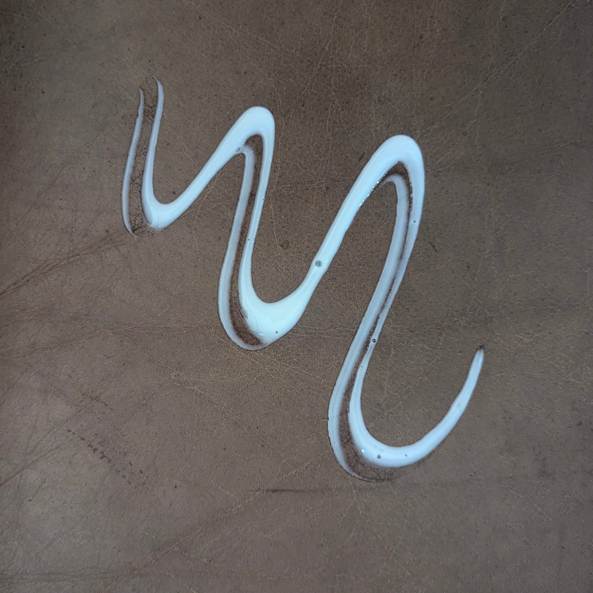 Picture of swirl of white leather conditioner on leather cushion