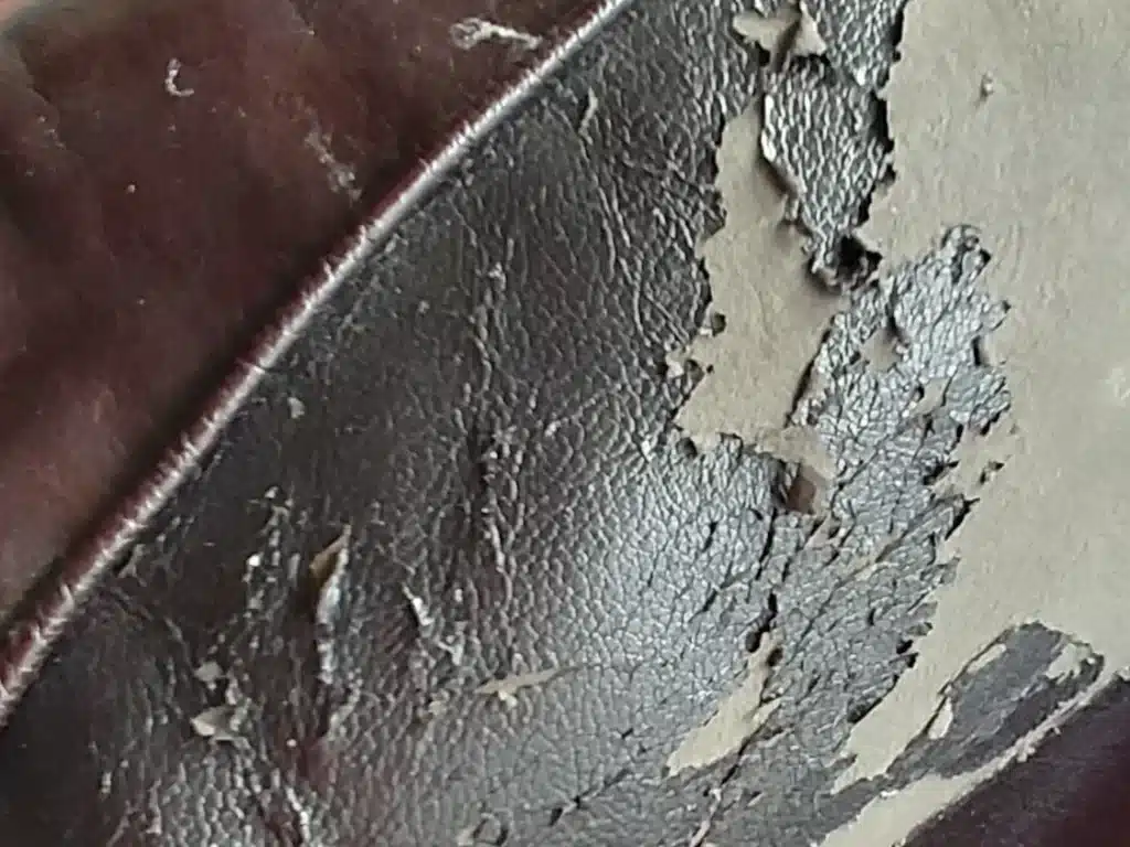 Picture of back of brown leather couch with peeling, flaking bonded leather
