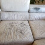 Close-up photo of scratches, body oil damage on white leather couch