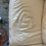 Close-up of leather couch cushion showing cracks and wear before repair