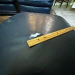 Picture of leather ottoman with large hole that began as a small pencil puncture 30 years ago